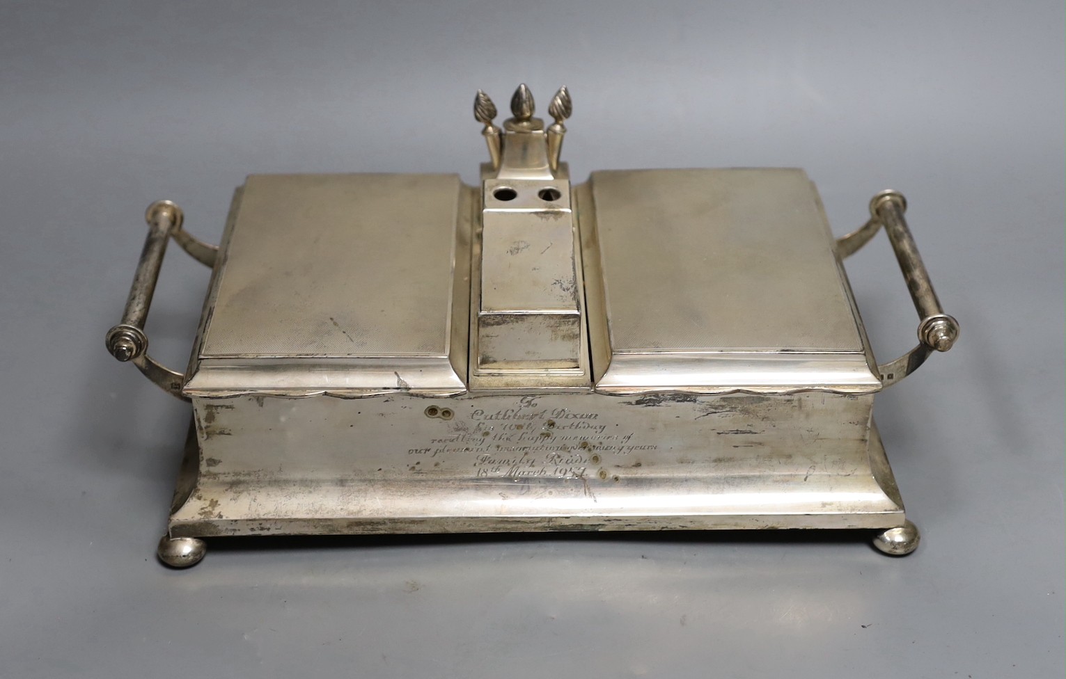 A George V silver mounted two handled desk top twin cigarette box incorporating a cigar cutter and lighters, with 1957 presentation inscription, Mappin & Webb, London, 1926, width 33.5cm.